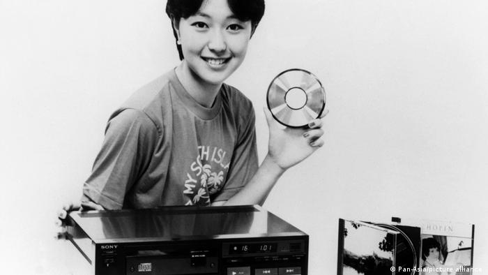 40 Jahre CD: Eine Frau hält lächelnd eine CD in der Hand, vor ihr steht ein Sony-CD-Player.