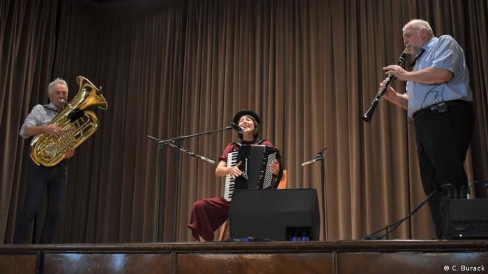 Das Trio Picon spielt auf einer Bühne, die Akkordeon-Spielerin singt dabei im Sitzen.