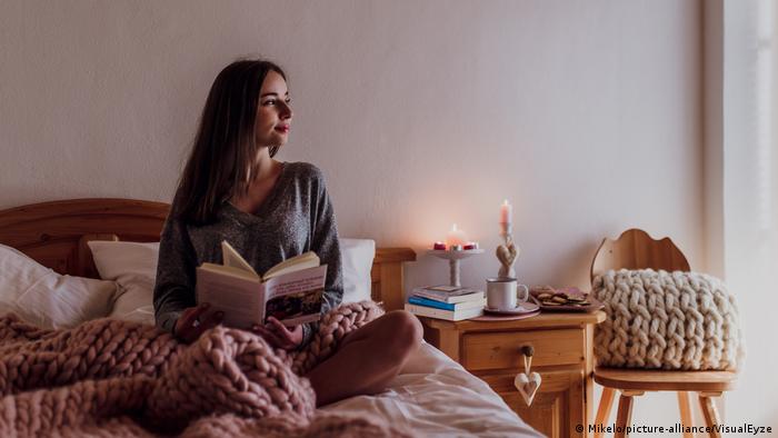 Frau sitz im Bett und liest ein Buch