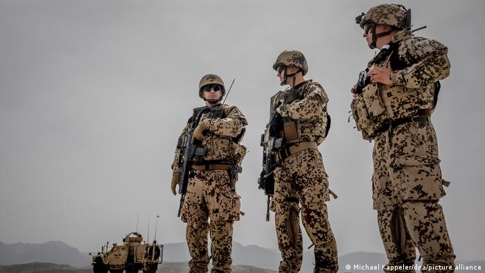 Bundeswehr-Soldaten mit Maschinengewehren und schusssicheren Westen bewachen einen Militär-Konvoi in Afghanistan.