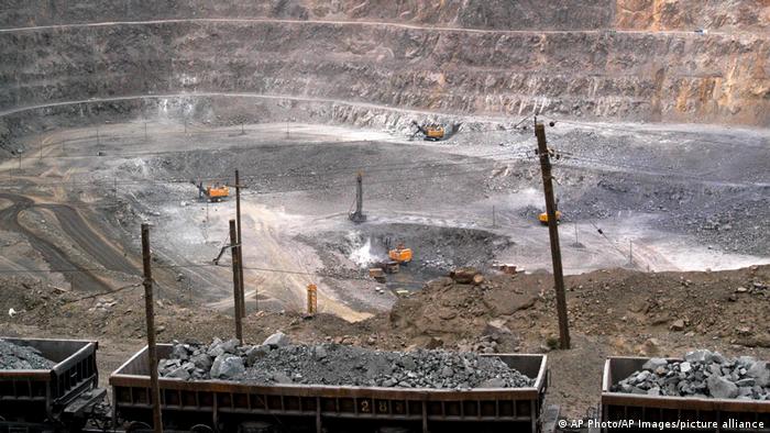 Das Foto zeigt Minenarbeiter, die in der Mongolei in einem Tagebau seltene Erden abbauen. Im Vordergrund sind gefüllte Eisenbahnwaggons zu sehen. 