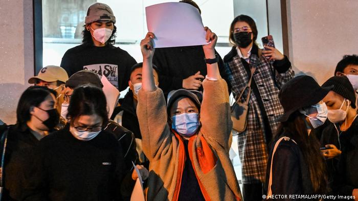 Eine Gruppe von Menschen protestiert mit hochgehaltenen weißen Papierblättern gegen Chinas Null-COVID-Politik