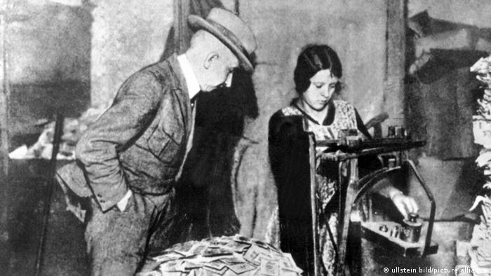 Ein Mann schaut einer jungen Frau dabei zu, wie sie Geldscheine wiegt