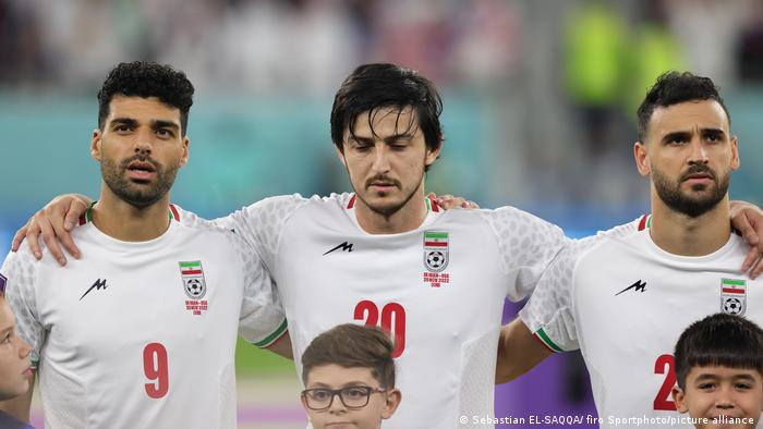 Irans Nationalspieler Sardar Azmoun steht bei der WM in Katar mit gesenktem Blick, und unbeweglichen Lippen während die iranischen Hymne gespielt wird
