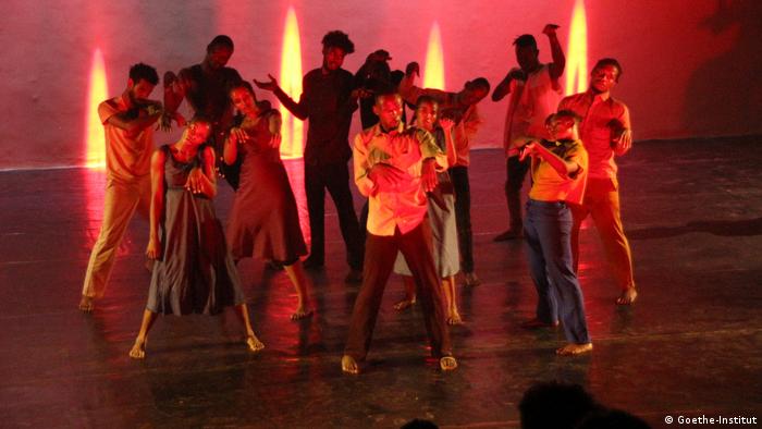 Sudanesische Tänzerinnen und Tänzer auf der rot beleuchteten Bühne 