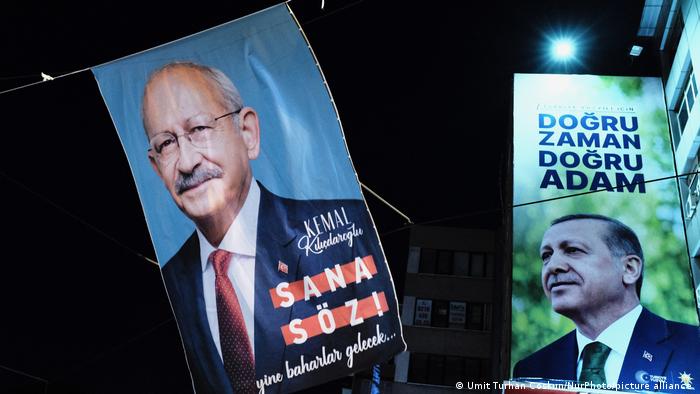 Ein Wahlplakat von Kemal Kilicdaroglu neben einem Wahlbanner von Recep Tayyip Erdogan auf einer Straße bei Nacht